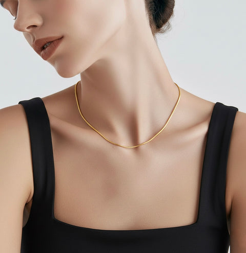Woman wearing a B.Tiff C030G gold coil chain necklace against a neutral background