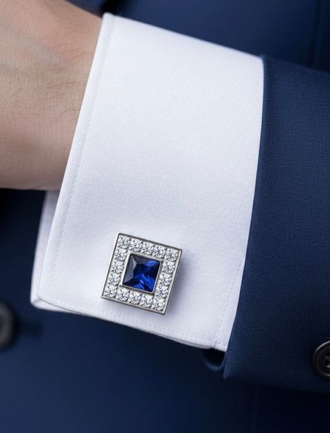Cufflink with a blue gemstone on a white cuff against a dark suit background