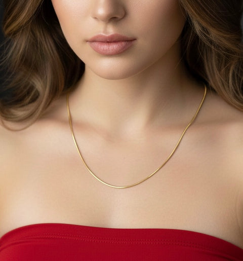 18K Gold plated octagonal herringbone necklace 1mm width worn by a woman in a red sleeveless top and long dark brown curly hair