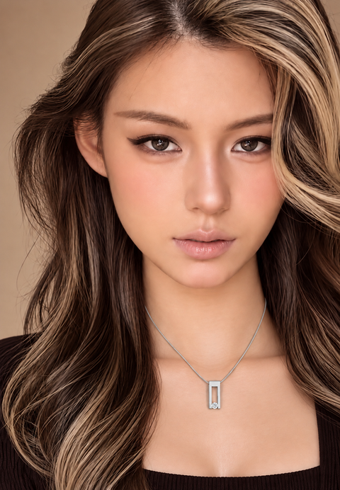 A close-up portrait of a woman with long brown and blonde highlighted hair, wearing a delicate B.Tiff PT089W silver chain necklace with a rectangular silver pendant on a warm beige background.