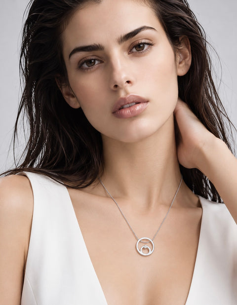 A close-up of a woman with dark hair wearing a B.Tiff PT105W silver double-ring pendant necklace and a white sleeveless top, set against a light gray background.