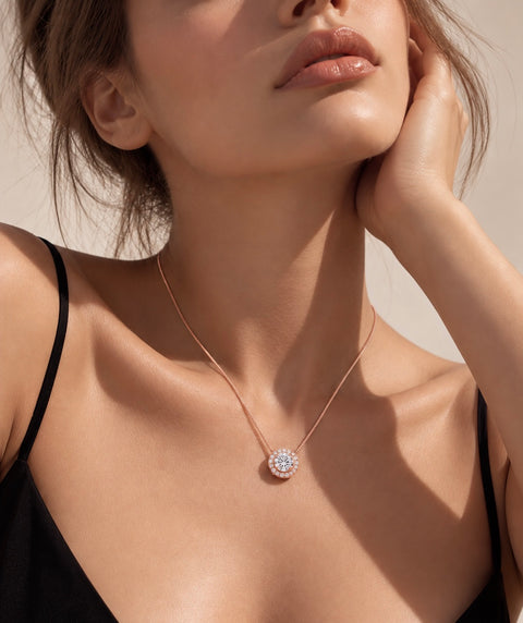 A close-up lifestyle shot of a model wearing a delicate rose gold necklace with a B.Tiff PT125RG circular pavé pendant on a warm beige background.