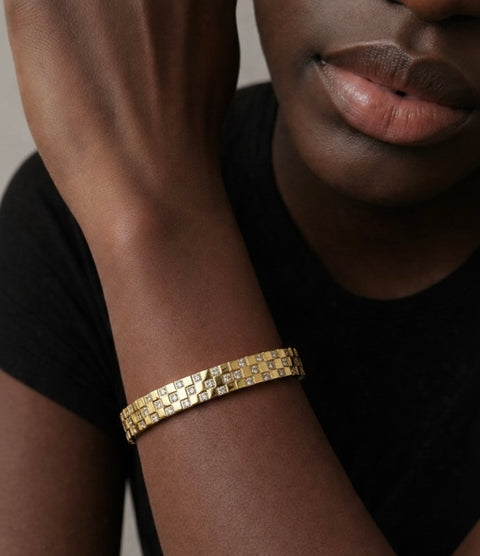 B.Tiff BG104G Trellis 18K Gold plated bangle bracelet on a black male wrist with a neutral background