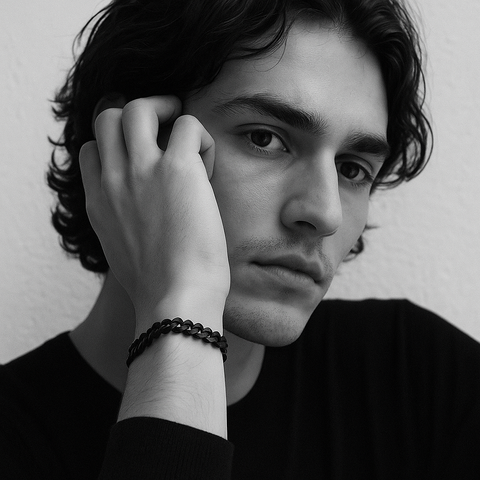 Black and white portrait of a person with one hand near their face, wearing a B.Tiff BG138B black 6mm cuban link bracelet.