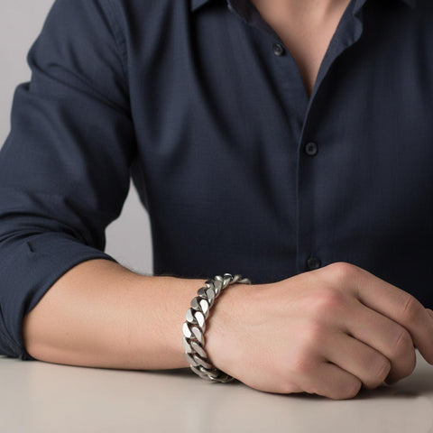A male wearing a B.Tiff BG160W silver 16mm Cuban link chain bracelet on a neutral background
