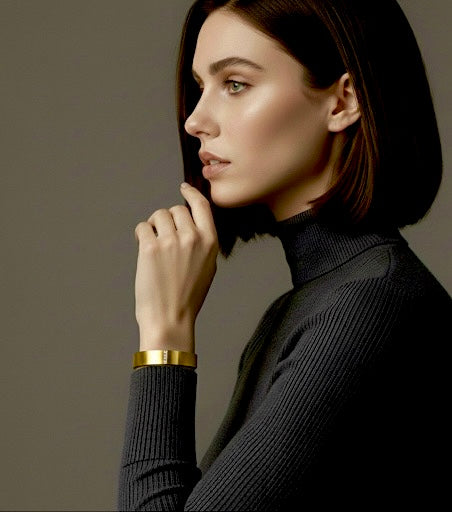 Woman wearing a black turtleneck and B.Tiff BG223G 18k gold plated bangle bracelet against a neutral background