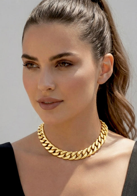 Woman wearing a B.Tiff C160G 16mm 18k gold plated Cuban chain necklace against a neutral background