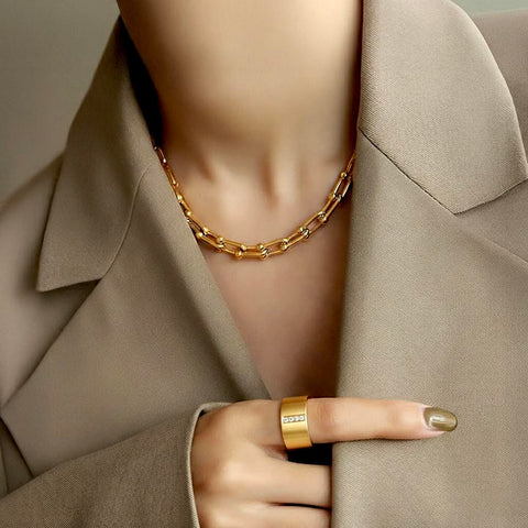 Woman wearing a B.Tiff C525G 18K gold plated cheval link chain necklace and B.Tiff RG223G ring with a neutral background