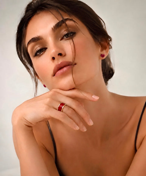 Woman with hand on chin wearing red earrings and B.Tiff RG800RGR wide ring against a neutral background